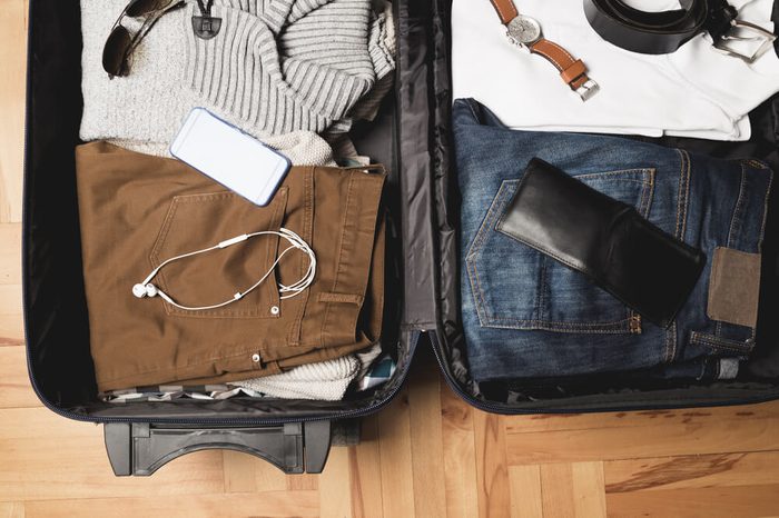 Open traveler's bag with men clothing, accessories, watch, watch and belt. Travel and vacations concept.