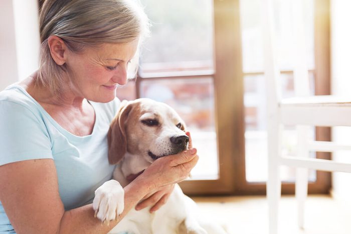 Senior woman with her dog inside of her house.