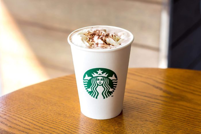 Bangkok, Thailand - December 21, 2017 : Starbucks Hot chocolate with whipping cream in white paper cup on wooden table background with copy space.