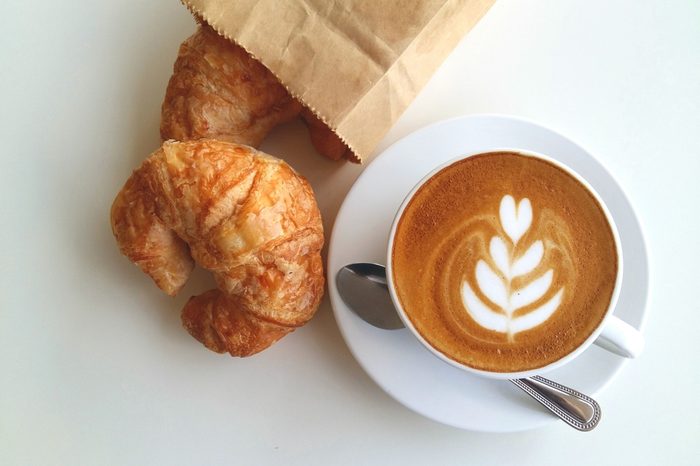 Latte art coffee with croissant so delicious on white