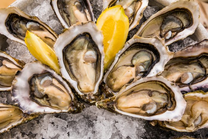 Opened Oysters on metal plate with ice and lemon.