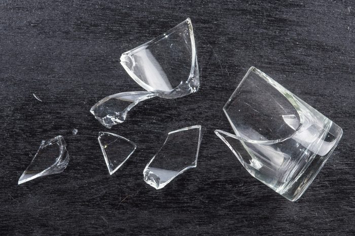 broken glass on dark wood background, concept of danger