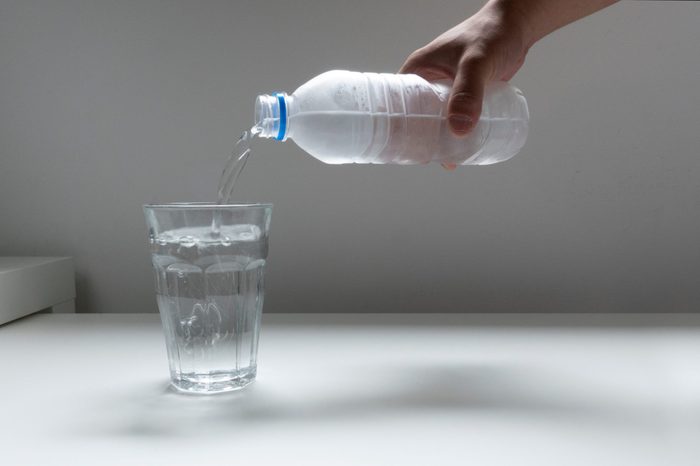 Image picture pouring plastic bottle of water into glass glass