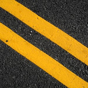 Yellow lines run parallel on dark asphalt, indicating a road or parking lot.