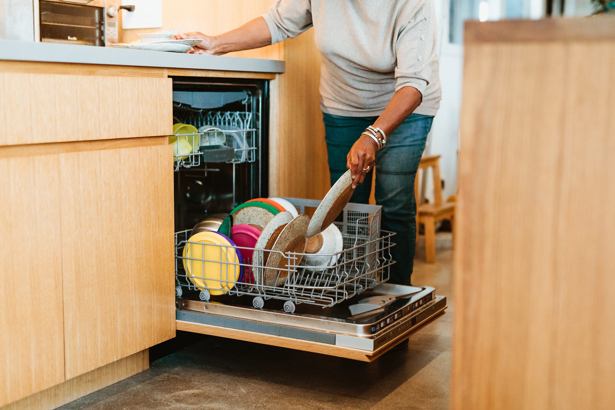 Senior woman keeping plates in dishwasher at home
