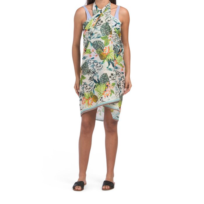 A person wearing a tropical-patterned sarong stands in sandals on a plain white background.