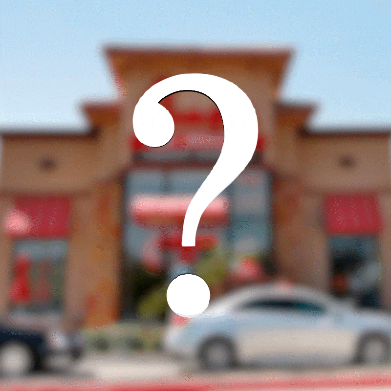 Question mark overlaying a blurred fast-food restaurant, with cars passing by outside.