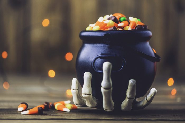Skeleton hand holding cauldron with candy for halloween party decor