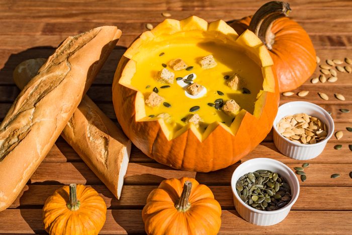 Pumpkin soup in shell served with bread and roasted pumpkin seeds