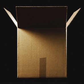 A cardboard box sits open, illuminated by light, surrounded by a dark background.