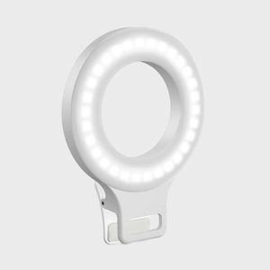 A circular LED ring light, glowing brightly, is attached to a clip. The background is plain gray.