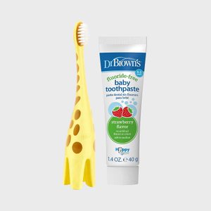 Yellow giraffe toothbrush stands upright beside a tube of fluoride-free baby toothpaste. Background is plain white.
