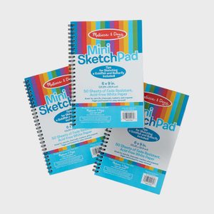 Sketchpads lie overlapping, with spiral bindings side-by-side, against a plain backdrop. The cover text describes features like fade-resistant, acid-free paper for drawing.