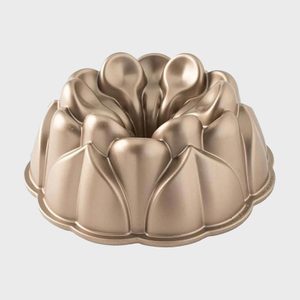 Bundt pan is resting; featuring a smooth, intricate design; on a plain white background.