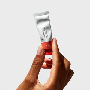 A hand holds a small tube labeled 
