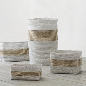 Woven baskets rest on a wooden floor, featuring alternating white and natural brown horizontal stripes, against a plain white background.