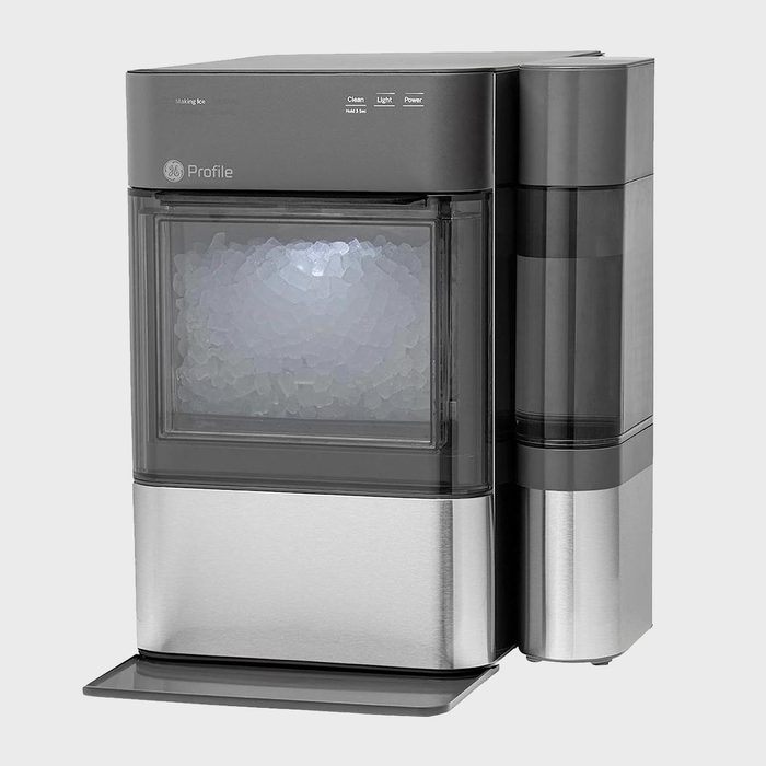 Ice maker producing ice, housed in a sleek, modern design, set in a minimalistic indoor space. Upper panel displays power and light indicators.