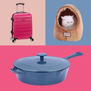Pink suitcase stands upright, a white cat rests in a cozy brown pet bed, and a blue Cuisinart skillet sits against colorful backgrounds.