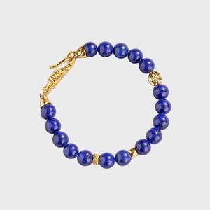 Blue beaded bracelet with gold accents forms a circle against a plain white background.