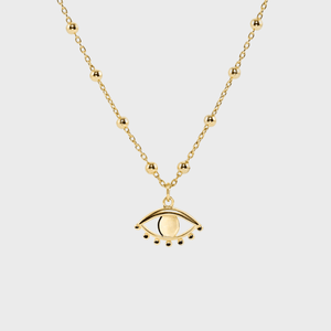 Gold necklace displaying an eye-shaped pendant with small dots, set against a plain white background.