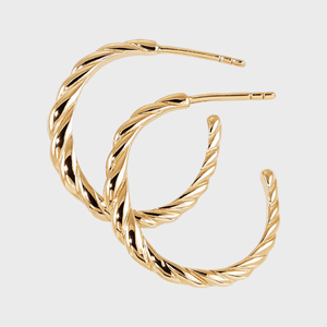 Gold twisted hoop earrings lying against a plain white background.
