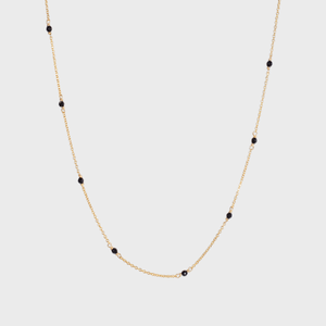 Gold chain necklace; adorned with small black beads; displayed on a plain white background.