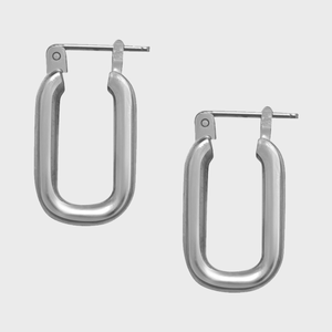 Silver rectangular earrings lie on a plain white background, displaying a smooth, polished surface and hinged hooks for fastening.