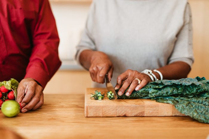 Woman chopping chard on cutting board by husband