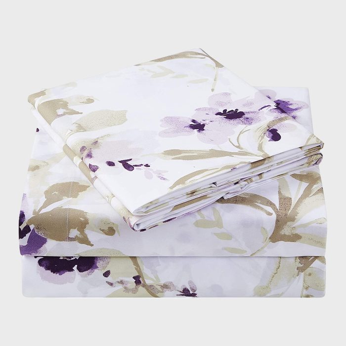 Folded floral-patterned sheets are stacked neatly, featuring pastel purple and beige flowers against a white background.
