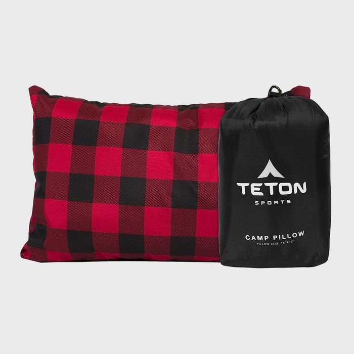 A plaid pillow lies next to a black bag. The bag reads 