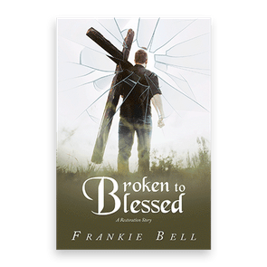 A man holds a cross, facing away, on grassy terrain with a cracked-glass effect. Text: 