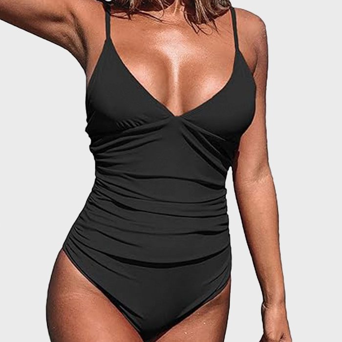 A person wearing a black one-piece swimsuit stands against a plain white background.