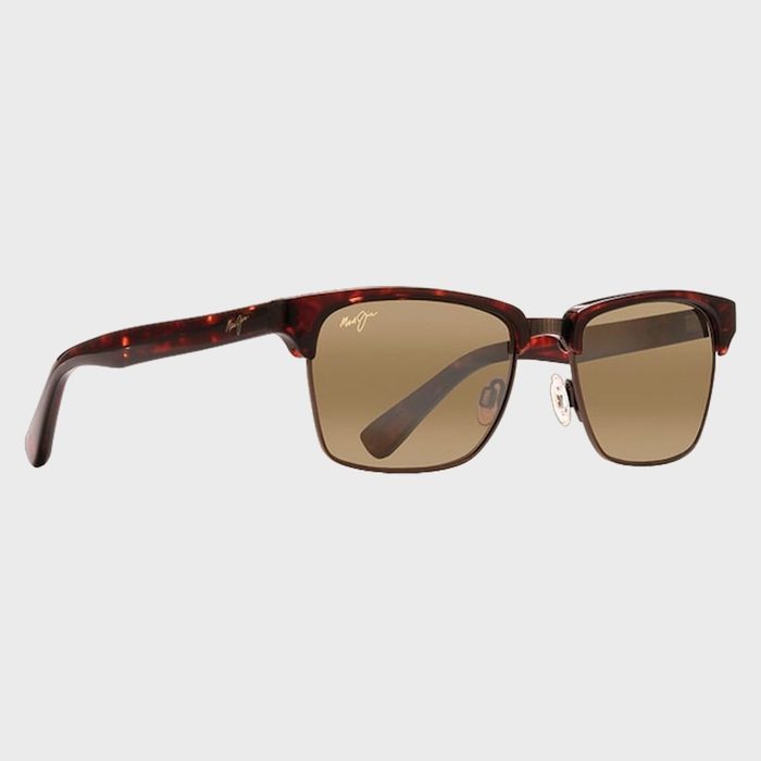 Sunglasses rest angled in a neutral, white background, featuring brown lenses and a tortoiseshell frame.