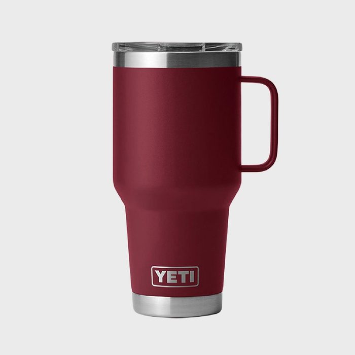A maroon YETI insulated travel mug stands upright with a handle, set against a plain gray background.
