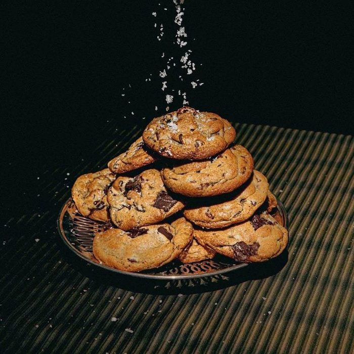Cookies stacked, sprinkled with salt, sit on a patterned plate against a dark background with striped surface.