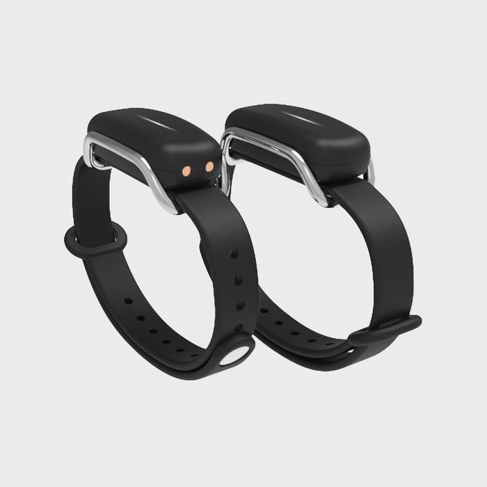 Two black fitness bands lie side by side, with sleek designs and adjustable straps, on a plain light gray background.