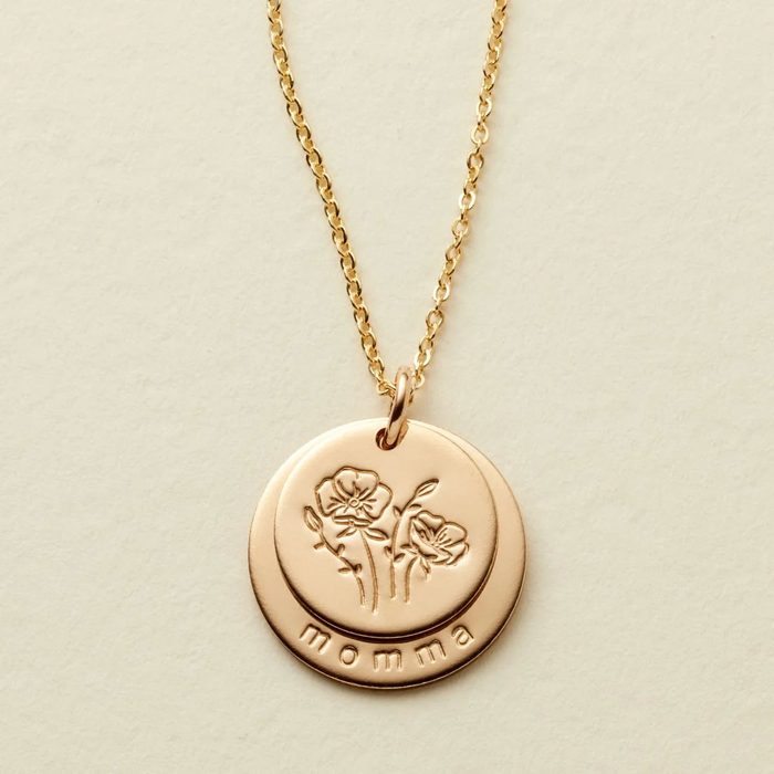 Gold necklace displays floral-engraved pendant reading 