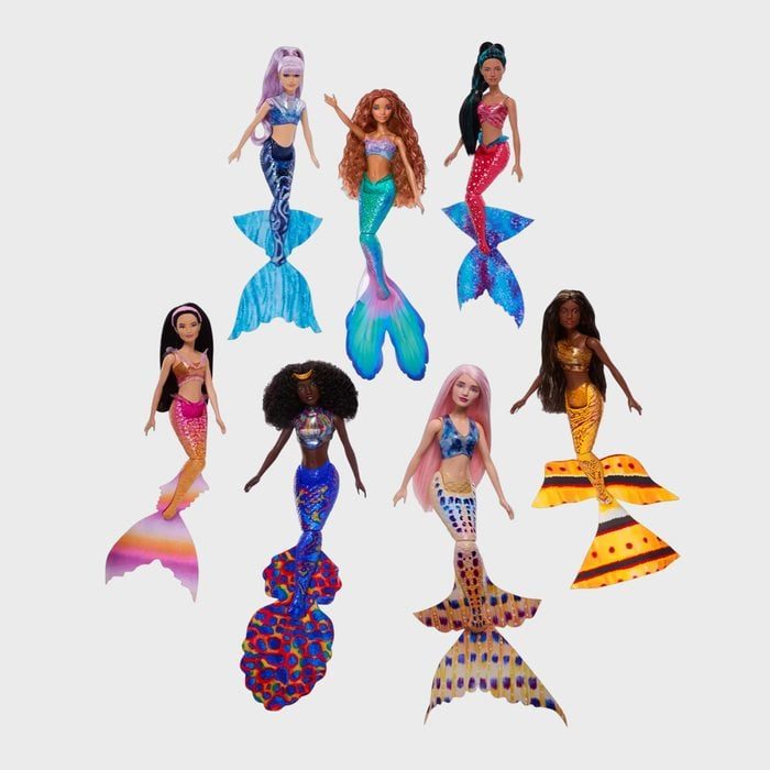 Diverse mermaid dolls stand, showcasing colorful tails, on a plain white background. Each doll has unique patterns and hairstyles, offering vibrant diversity.