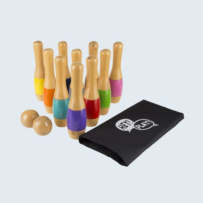 Wooden bowling pins stand arranged with colorful bands; two balls rest nearby, beside a black bag labeled 