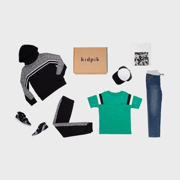 Clothing items are neatly arranged, including a hoodie, jeans, t-shirts, sneakers, and a cap, surrounding a 