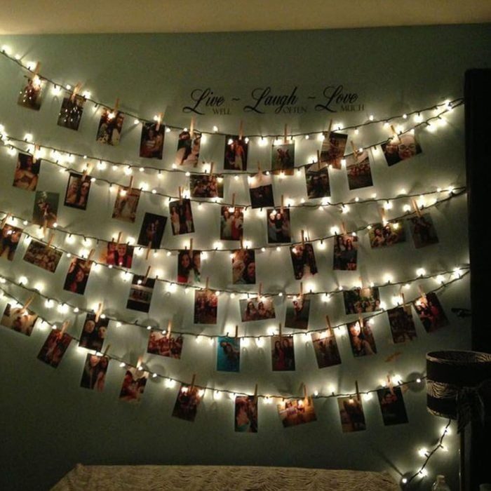 Photos hang clipped to string lights, adorning a wall. Above, text reads 
