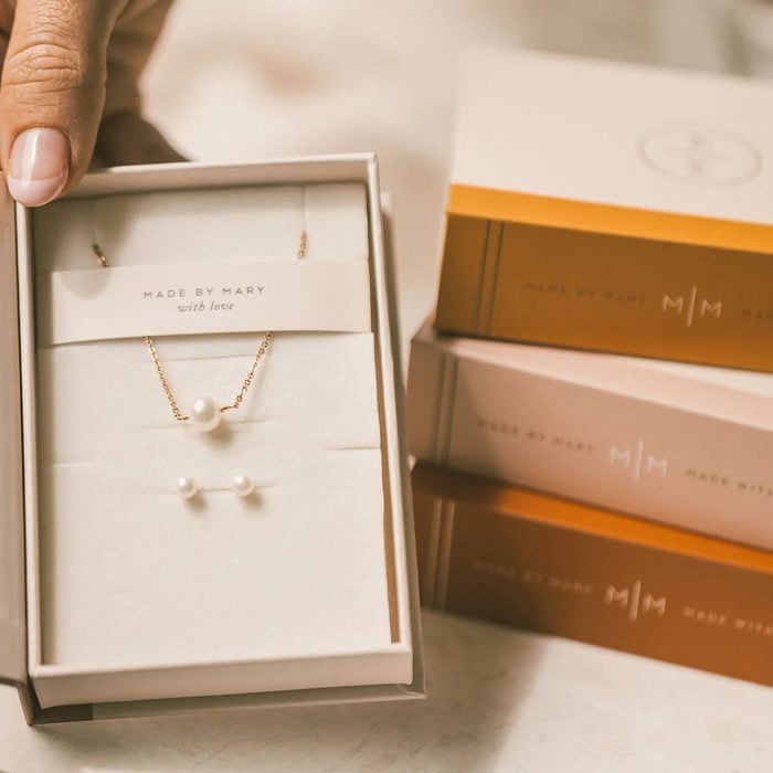 Necklace and earrings displayed in a box, featuring pearls, labeled 